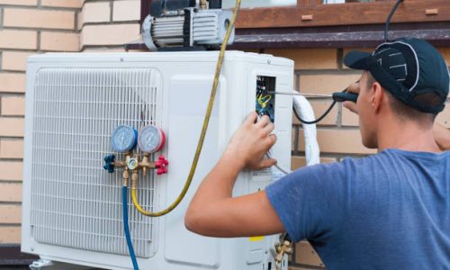 the worker installs the outdoor unit of the air conditioner on the wall of the house